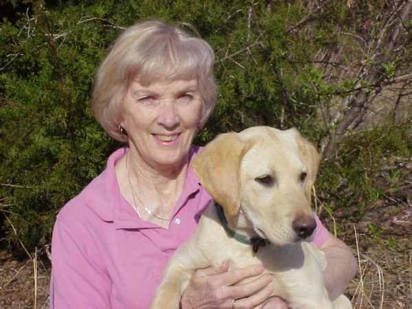 Barbara Lewis, director of Listen Up Pup, with a yellow Labrador Retriever