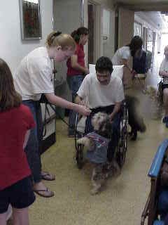 A therapy dog team walking through a residential facility with residents and staff